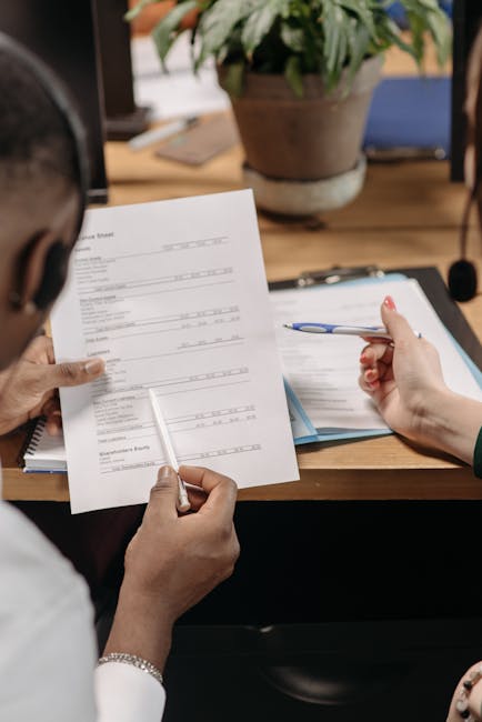 两位专业人士在办公室审查财务文件 Two professionals reviewing financial documents.