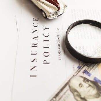 宠物保险 Pet Insurance 保险单、放大镜、玩具车和钱的近景 Insurance policy with magnifying glass, toy car, money.