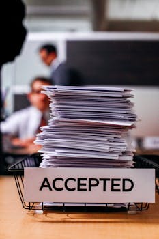 办公室中一堆贴有“已接受”标签的文件 Pile of papers with 'Accepted' label.