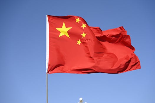 中国国旗在蓝天高高飘扬 Chinese national flag flying high against clear blue sky.