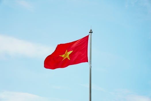 越南国旗在蓝天下飘扬 Vietnam national flag waving high on a flagpole.