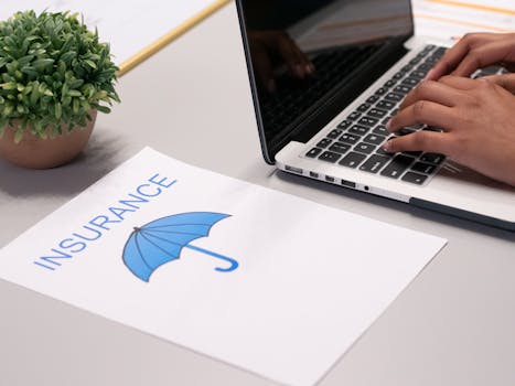 电子保险 Insurance on Laptop 笔记本电脑上保险文件的双手 Hands typing on laptop with insurance document.